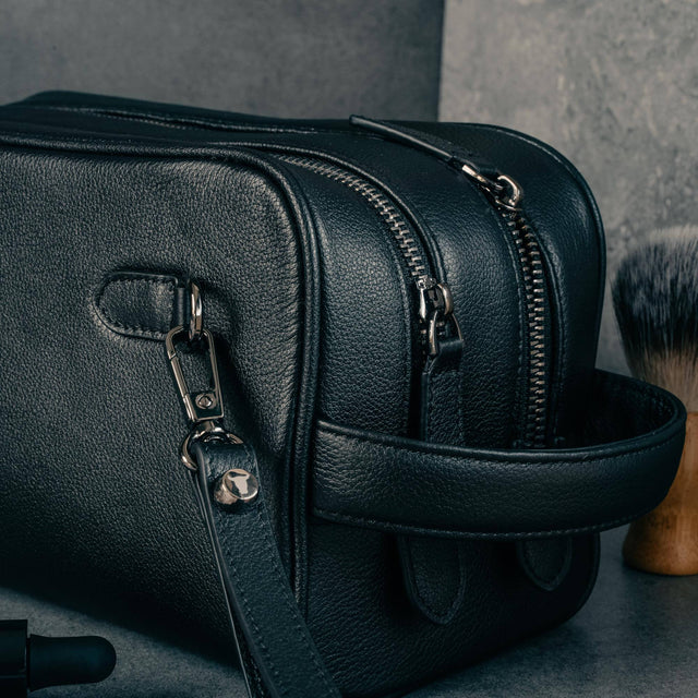 Double zipped compartments, harry handle and detachable strap on the Black Leather Wash Bag